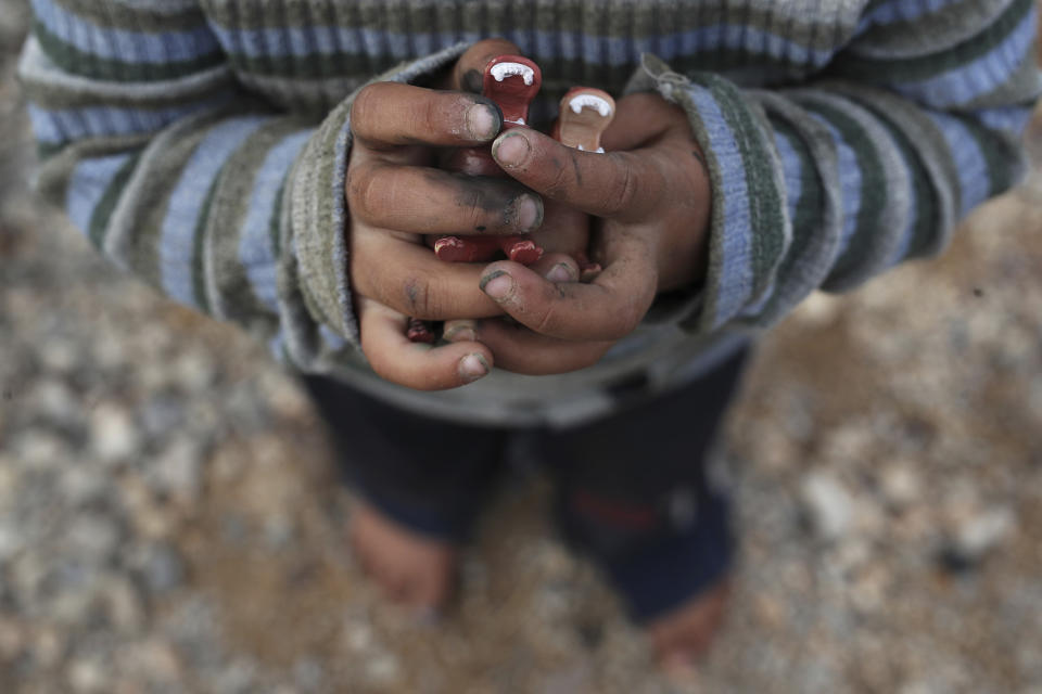 A Syrian boy clutches toy animals in his hands
