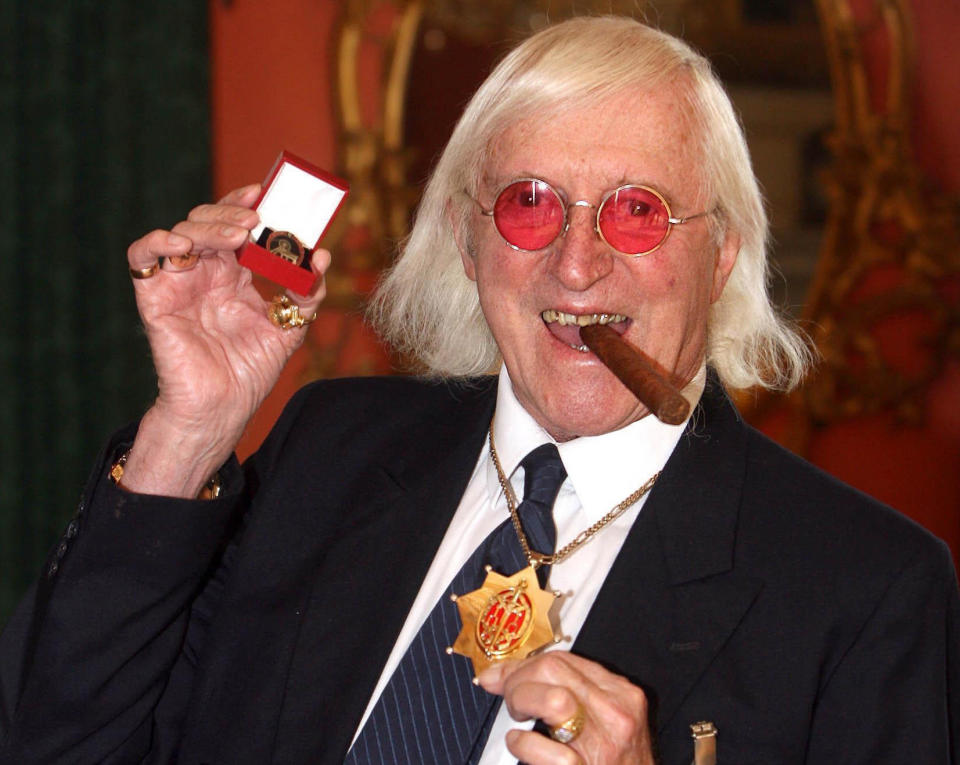 FILE - This March 25, 2008 file photo shows Jimmy Savile holding a medal in London. At Savile's funeral in 2011, the priest delivering the homily was emphatic: the DJ and television host "can face eternal life with confidence." But a year on, Savile's reputation is in ruins. Police have branded him one of Britain's worst sex offenders, accused of assaulting underage girls over half a century. Like those who feted and praised him on that November day, millions are wondering: How could he have duped so many for so long? (AP Photo/Lewis Whyld/PA Wire)