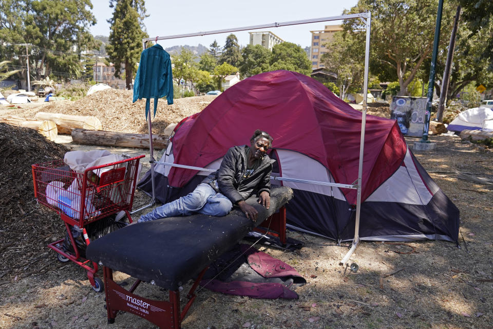 Ken Swofford, 69, rests on a massage table outside his tent at People's Park in Berkeley, Calif., Tuesday, Aug. 16, 2022. The three-acre site's colorful history, forged from University of California, Berkeley's seizure of the land in 1968, has been thrust back into the spotlight by the school's renewed effort to pave over People's Park as part of a $312 million project that includes sorely needed housing for about 1,000 students. (AP Photo/Eric Risberg)