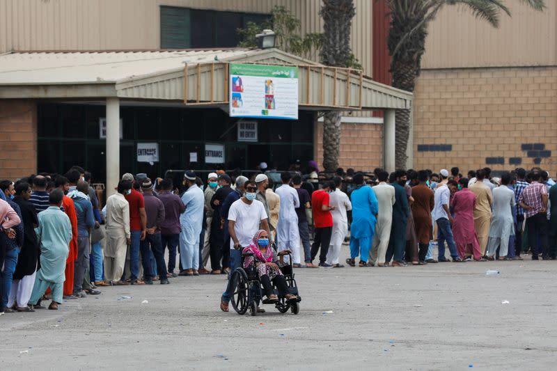 Residents line up to receive a vaccine against COVID-19 at a vaccination facility in Karachi