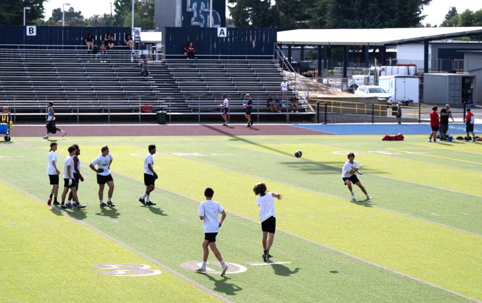 Enochs team members warm up before varsity passing league at Downey High School in Modesto, Calif., Tuesday, June 27, 2023.
