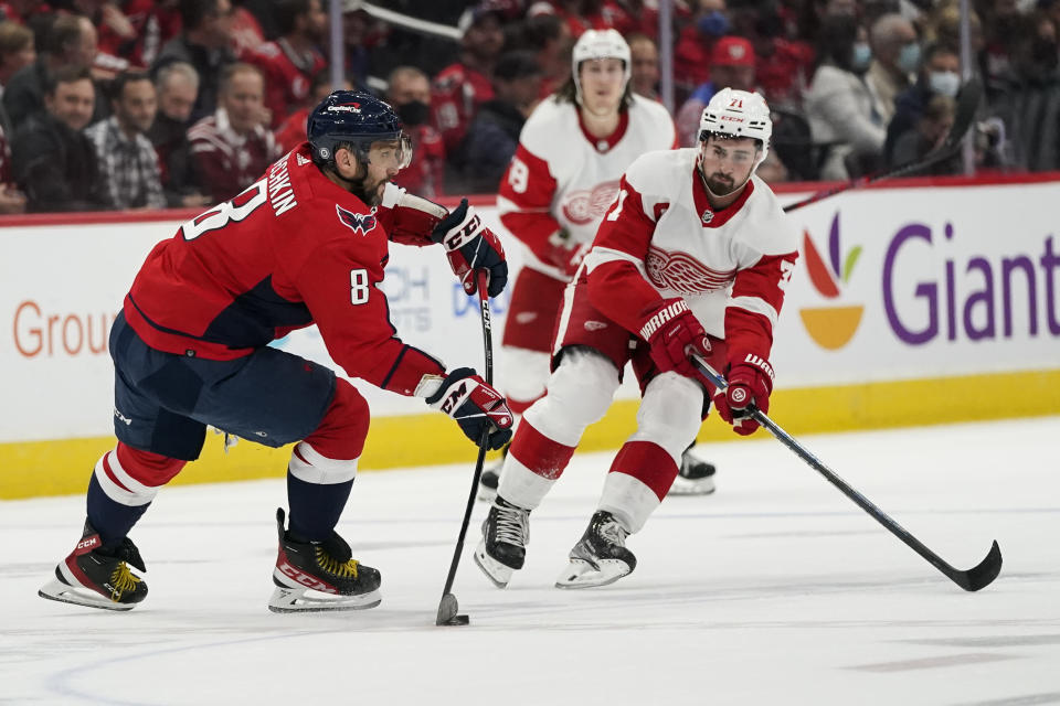Washington Capitals left wing Alex Ovechkin (8) passes the puck past Detroit Red Wings center Dylan Larkin (71) in the first period of an NHL hockey game, Wednesday, Oct. 27, 2021, in Washington. (AP Photo/Alex Brandon)