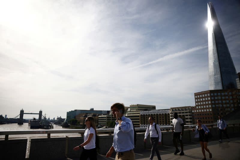 Commuters walk over London Bridge during warm weather in London