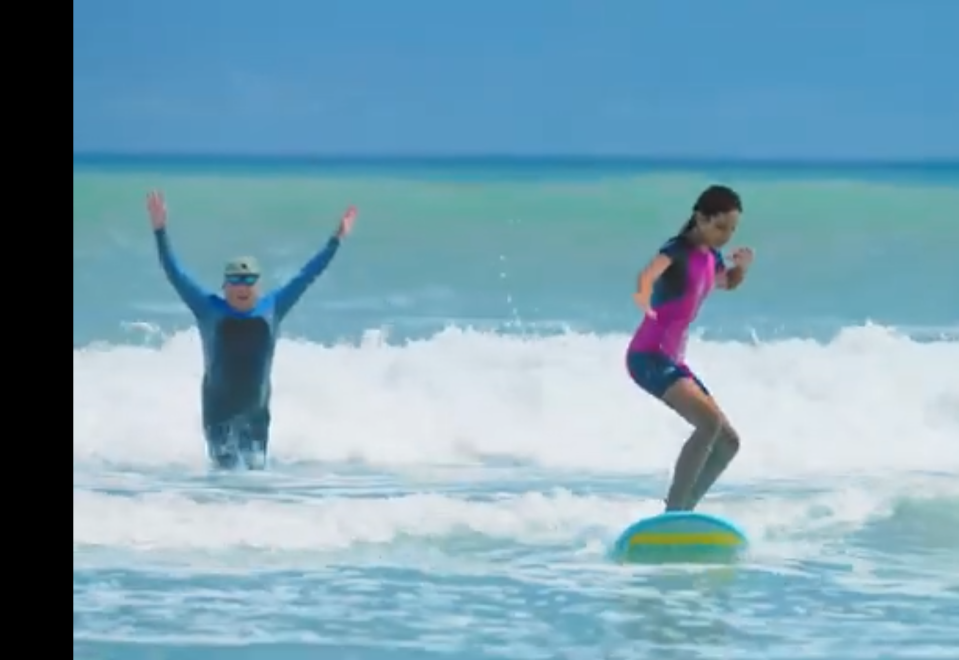 A father celebrates as his daughter learns to surf in a TV ad as part of the Daytona Beach Area CVB's "Beach On" tourism campaign. The ad was honored by Visit Florida with a Flagler Award.