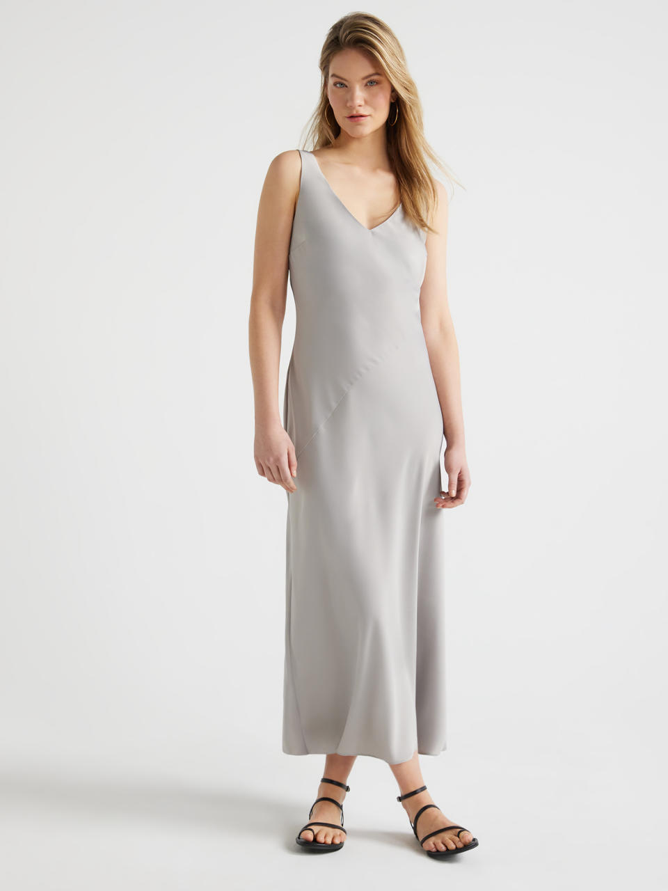 people in a sleeveless v-neck midi dress and strappy sandals standing against a neutral backdrop