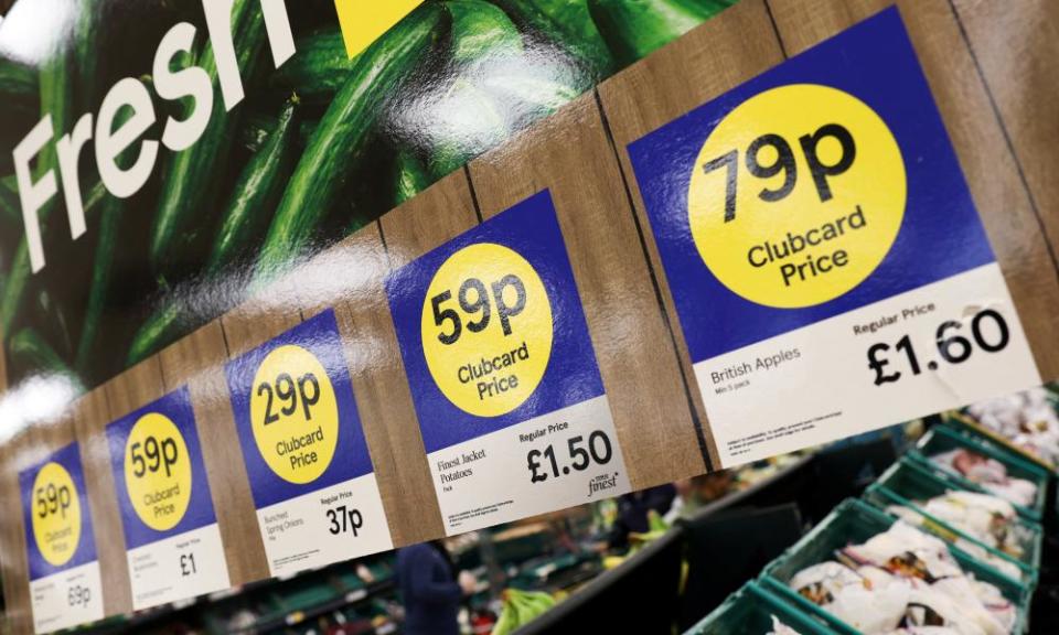 A row of special offer adverts above the fresh produce shelves at a Tesco, showing heavy discounts for the ‘Clubcard price’ compared with the regular price