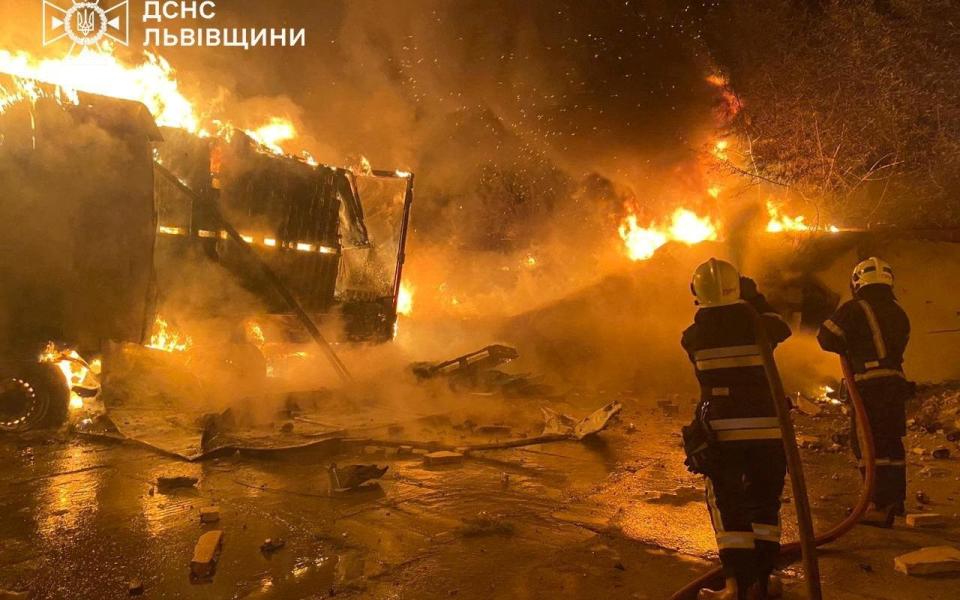 Firefighters extinguish fire in trucks at a site where warehouse facilities were hit during a Russian drone strike