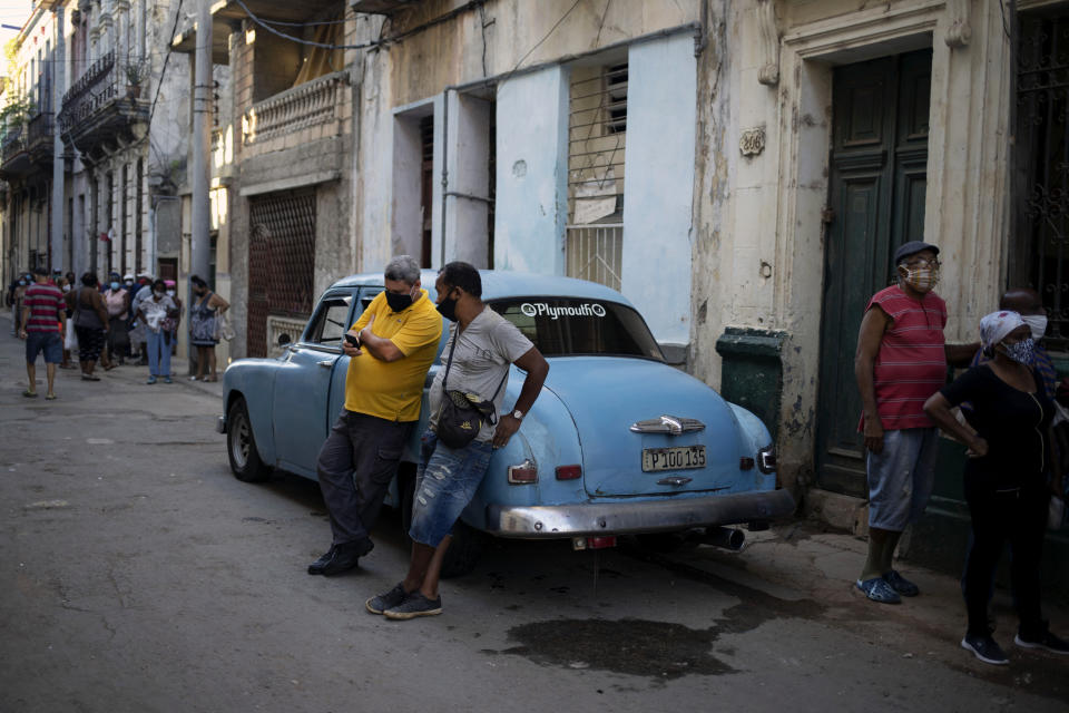 Un hombre mira su teléfono celular mientras otros esperan en fila en una tienda de abarrotes en La Habana, Cuba, el martes 13 de julio de 2021. El presidente cubano Miguel Díaz-Canel acusó a los cubanoamericanos de usar las redes sociales para estimular las protestas antigubernamentales en todo el país y las autoridades cubanas bloquearon algunas aplicaciones de redes sociales. (AP Foto/Eliana Aponte)