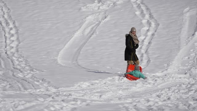 A mom pulls her daughter up a hill as they sled Tuesday, Jan. 16, 2024, in Nashville, Tenn.