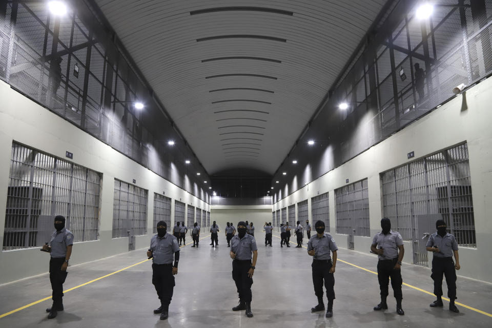 FILE - Prison guards stand outside holding cells at the Terrorism Confinement Center, a new "mega-prison" built especially for gang members, during a media tour in Tecoluca, El Salvador, Feb. 2, 2023. The government’s minister for justice and peace said the suspected gang members would never return to the streets, even though the thousands of those arrested during a state of emergency anti-gang campaign are still awaiting formal charges or a trial. (AP Photo/Salvador Melendez, File)