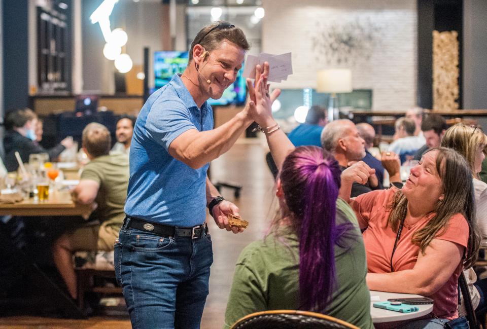 FILE - Mike Sleeper gives a high-five to a player after she gets an answer right during trivia night at the Crowne Plaza Hotel in North Augusta on Wednesday, March 24, 2021. Sleeper's trivia company will host games across the Augusta area for most of Masters Week.