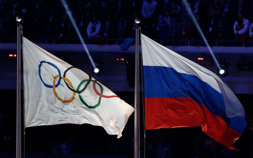 The Russian national flag, right, flies after it is hoisted next to the Olympic flag - AP /Matthias Schrader