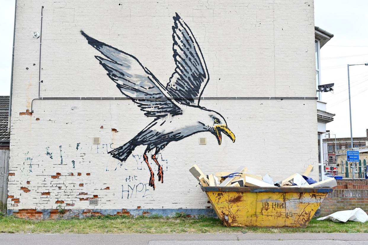 A stensil of a gull about to swoop down onto a carton of chips is the subject of a graffiti artwork bearing the hallmarks of street artist Banksy on a wall in Lowestoft on the East coast of England on August 8, 2021.