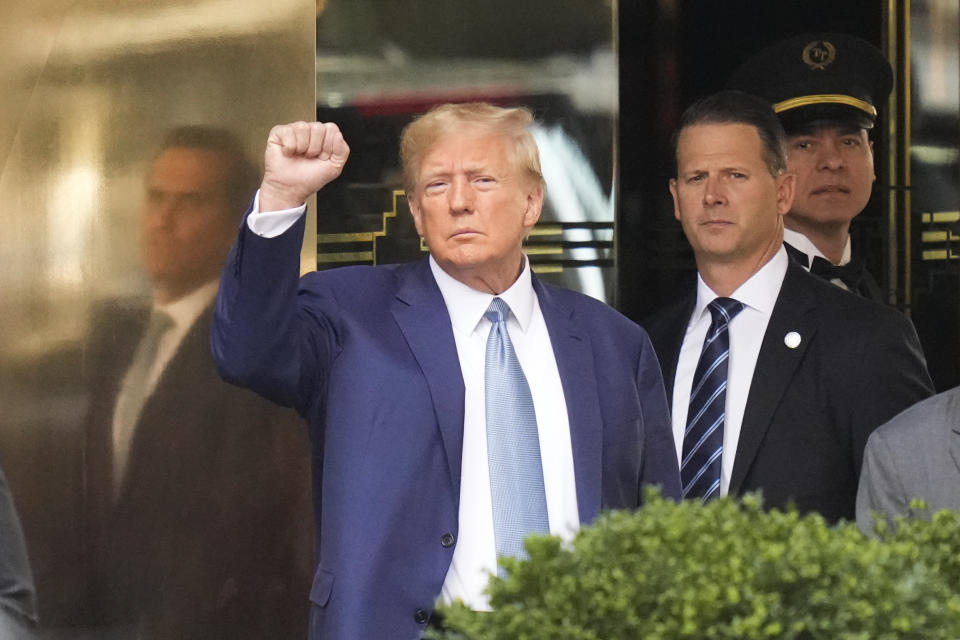 Former President Donald Trump, left, gestures as he leaves Trump Tower in New York, Thursday, April 13, 2023. (AP Photo/Seth Wenig)