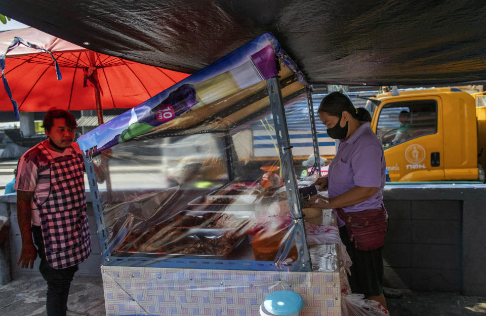 A street food vender standing behind plastic sheets to help curb the spread of the new coronavirus prepares a meal in Bangkok, Thailand, Tuesday, April 28, 2020. A month-long state of emergency remains enforced in Thailand to allow its government to impose stricter measures to control the coronavirus that has infected hundreds of people in the Southeast Asian country. (AP Photo/Gemunu Amarasinghe)