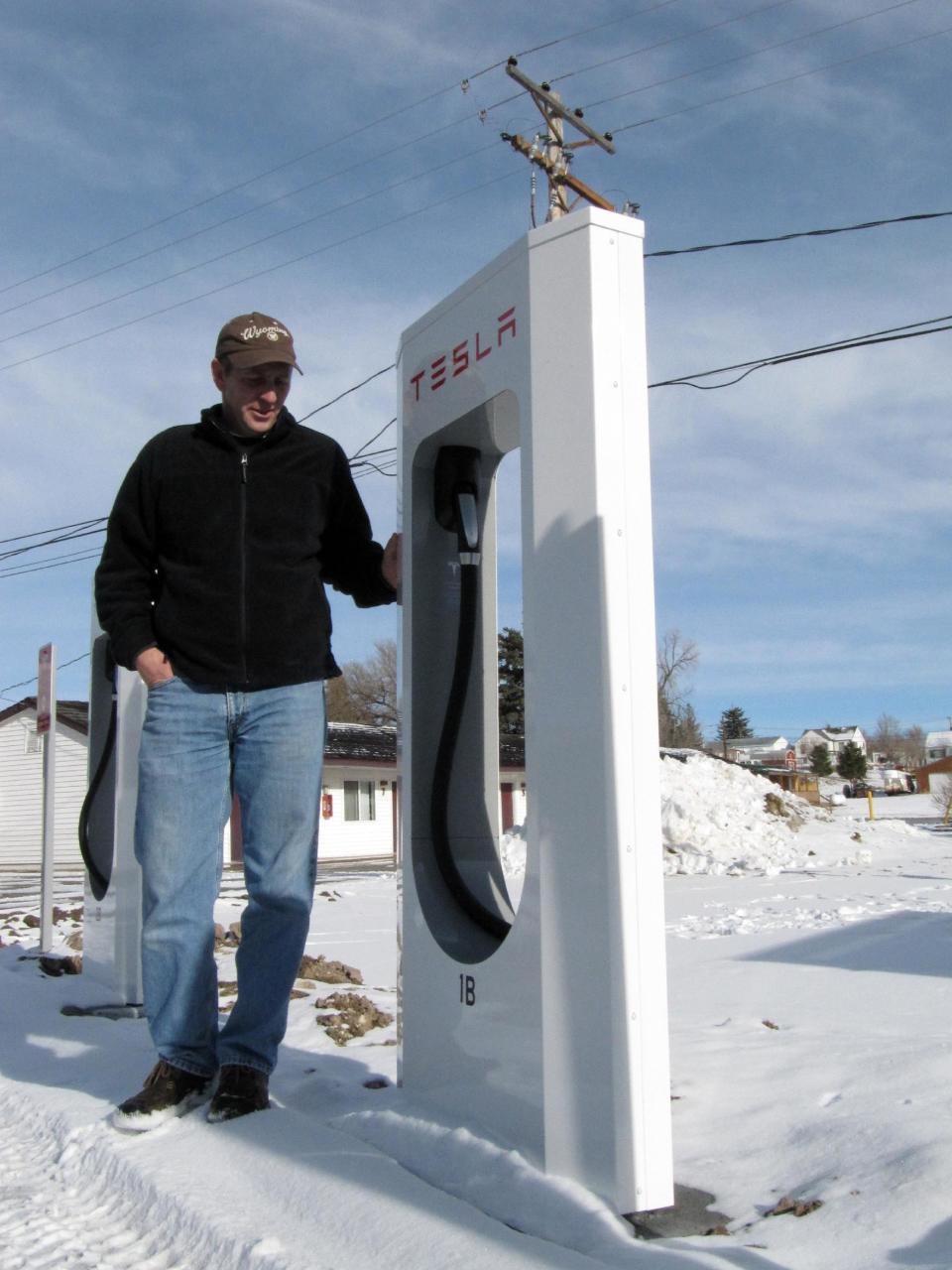 In this Jan. 2, 2014 photo, Mark Kupke, owner of the Covered Wagon Motel in Lusk, Wyo., stands next to one of four Tesla Supercharger units installed in December in the hotel courtyard. A Supercharger can recharge a Tesla's depleted battery pack to a 90-percent level within 45-50 minutes, several times faster than any other charging option for the electric cars. Lusk is on the route of Tesla's first network of coast-to-coast Supercharger stations. The quick-charge stations promise to make cross-country travel by Tesla much quicker and easier. (AP Photo/Mead Gruver)