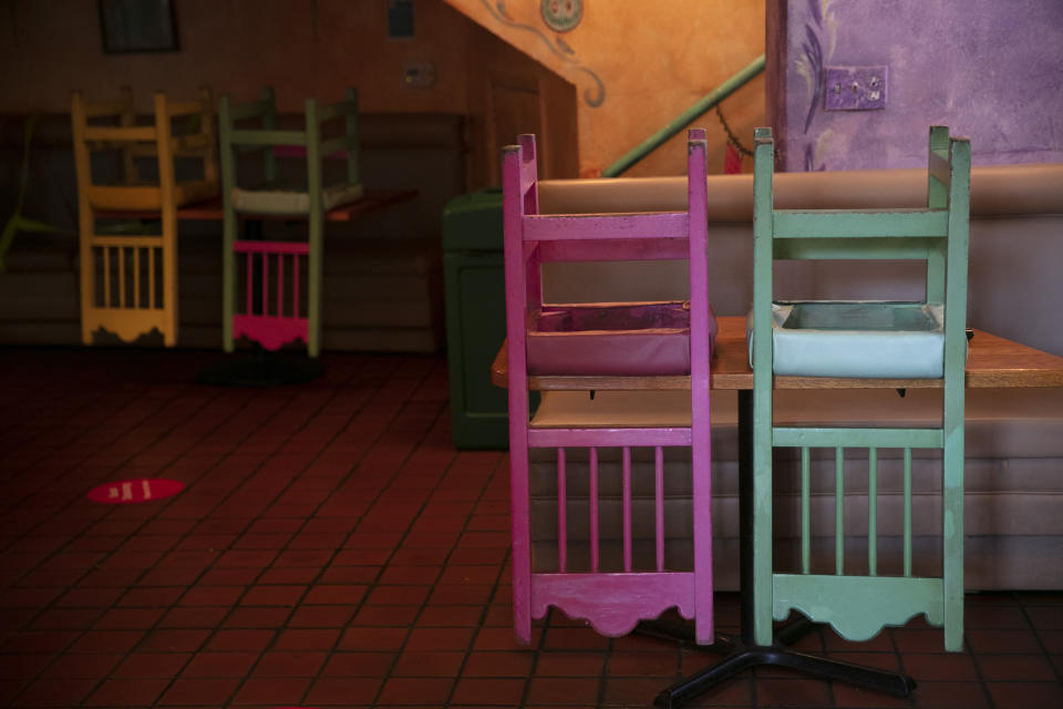 Colorful chairs are flipped over on dining tables at a Mexican restaurant on Olvera Street in Los Angeles, Monday, July 6, 2020. (AP Photo/Jae C. Hong)