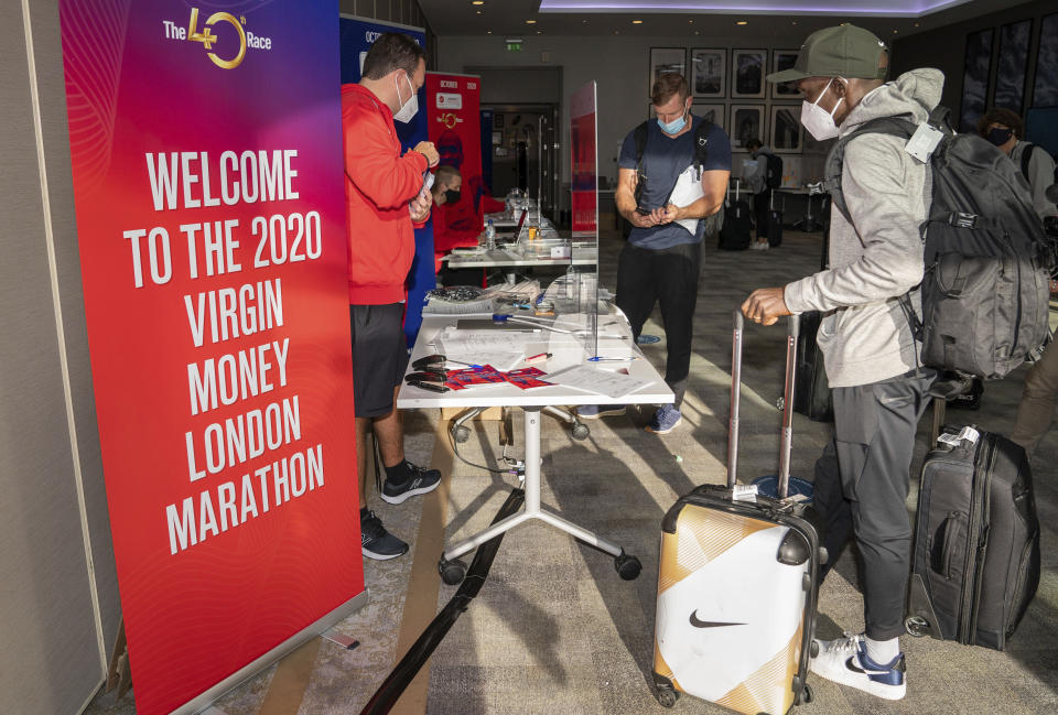 In this image issued by London Marathon Events, Kenya's Eliud Kipchoge registers at the official hotel and biosecure bubble in London, Monday Sept. 28, 2020, ahead of the elite-only 2020 London Marathon on Sunday Oct. 4. The 40th Race will take place on a closed-loop circuit around St James's Park in central London. (Bob Martin/London Marathon Events via AP)