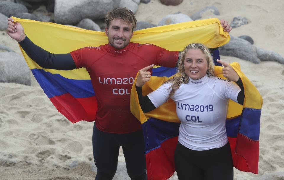 Giorgio Gomez and his sister Isabella Gomez, of Colombia, pose for photos after the pair both won a gold medal for paddle, in the women's and men's SUP surfing events, during the Pan American Games on Punta Rocas beach in Lima Peru, Sunday, Aug. 4, 2019. (AP Photo/Martin Mejia)