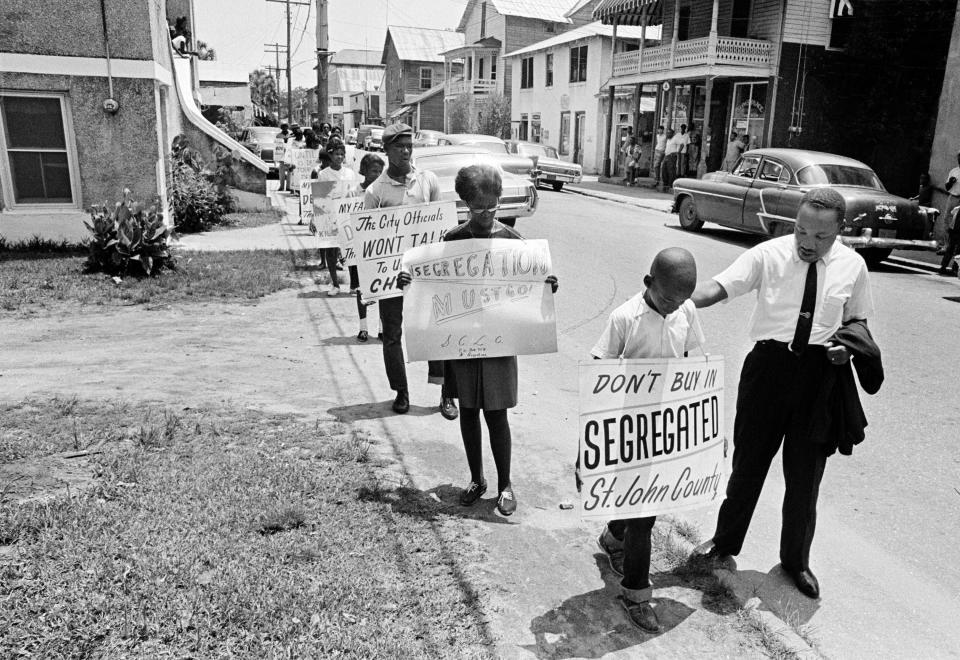 In June 1964 the Rev. Martin Luther King Jr. gives Eric James a pat on the back as a group of young picketers walk down Washington Street in St. Augustine.