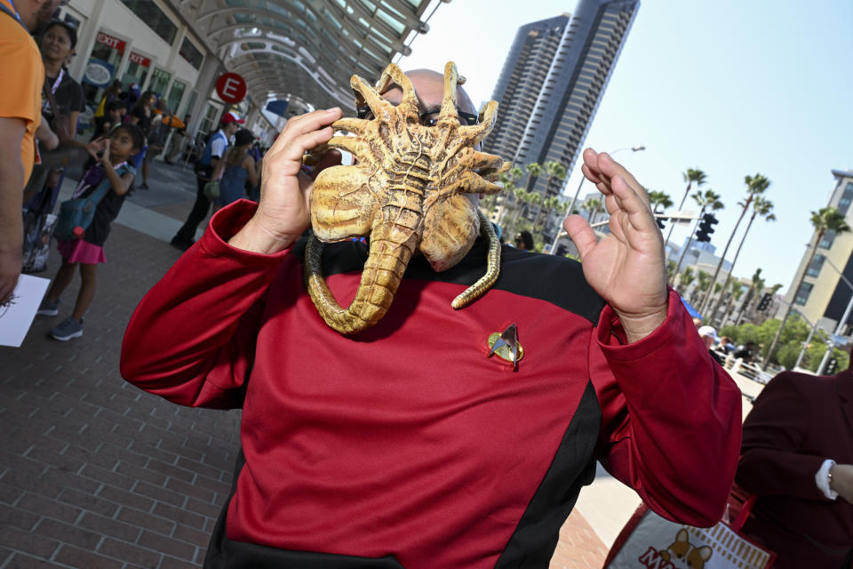 A cosplayer dressed as a Star Trek character being attacked by a facehugger from Alien.