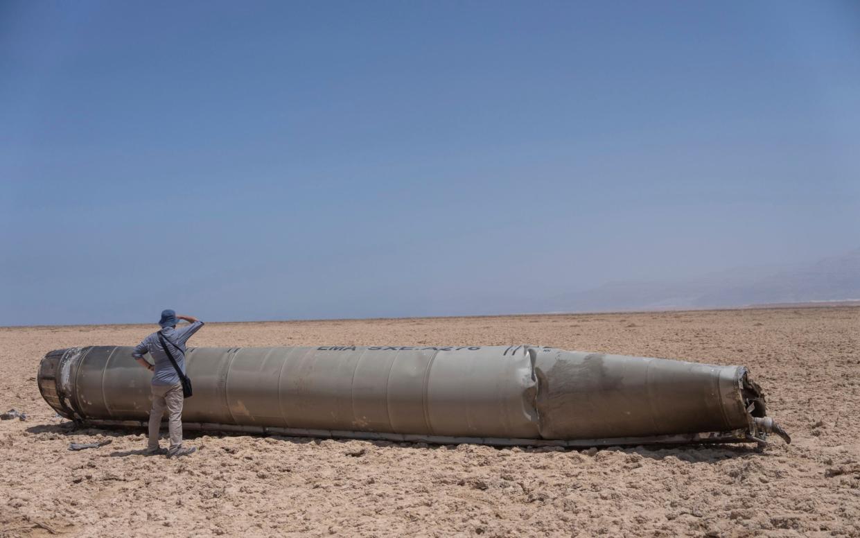 A photojournalist looks at part of an intercepted Iranian ballistic missile that fell near the Dead Sea in Israel on April 13