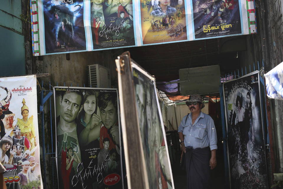 In this Tuesday, Aug. 13, 2013 photo, A Yaing Min, the "King of Cruelty," stands in his dimly lit office with its facade clad with local movie posters, in downtown Yangon, Myanmar. Each morning, the bad guys of Yangon and their brethren - all members of Ko Lu Chaw, or "Handsome Guy Group," effectively a trade union for cinematic villains - arrive at dawn. They take up position at outdoor breakfast stalls along 35th and 36th streets, a tightly packed enclave of video production houses, movie-poster design studios and worse-for-wear apartment buildings that serves as the tattered ground zero of the Burmese movie industry. Hoping for day work, they order coffee or tea, and they hope. (AP Photo/Wong Maye-E)