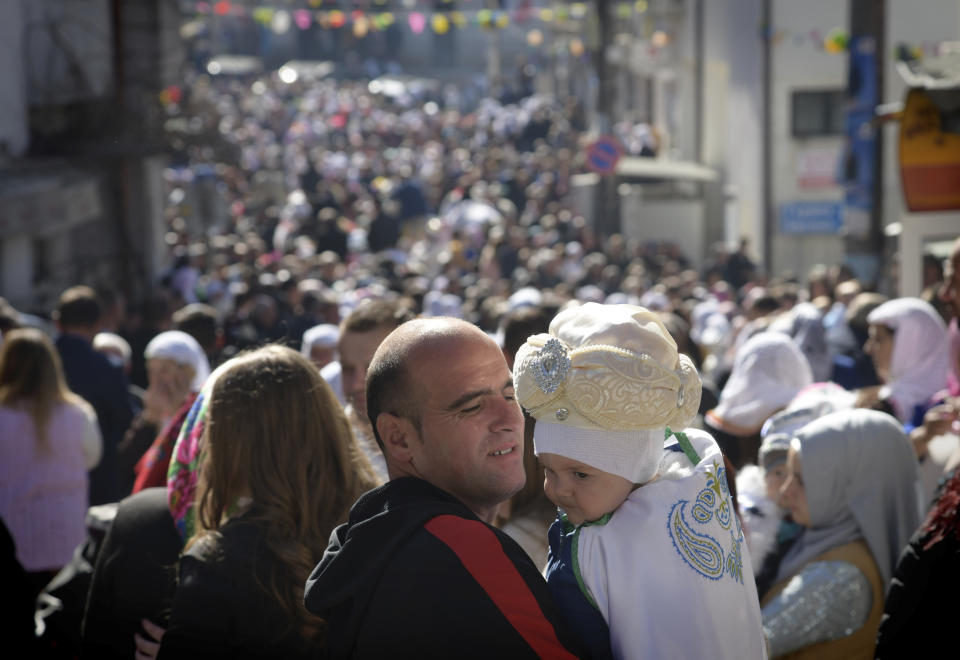 A father holds his son as they take part in a mass circumcision ceremony in the village of Ribnovo, Bulgaria, Sunday, April 11, 2021. Despite the dangers associated with COVID-19 and government calls to avoid large gatherings, Hundreds of people flocked to the tiny village of Ribnovo in southwestern Bulgaria for a four-day festival of feasting, music and the ritual of circumcision which is considered by Muslims a religious duty and essential part of a man's identity. (AP Photo/Jordan Simeonov)