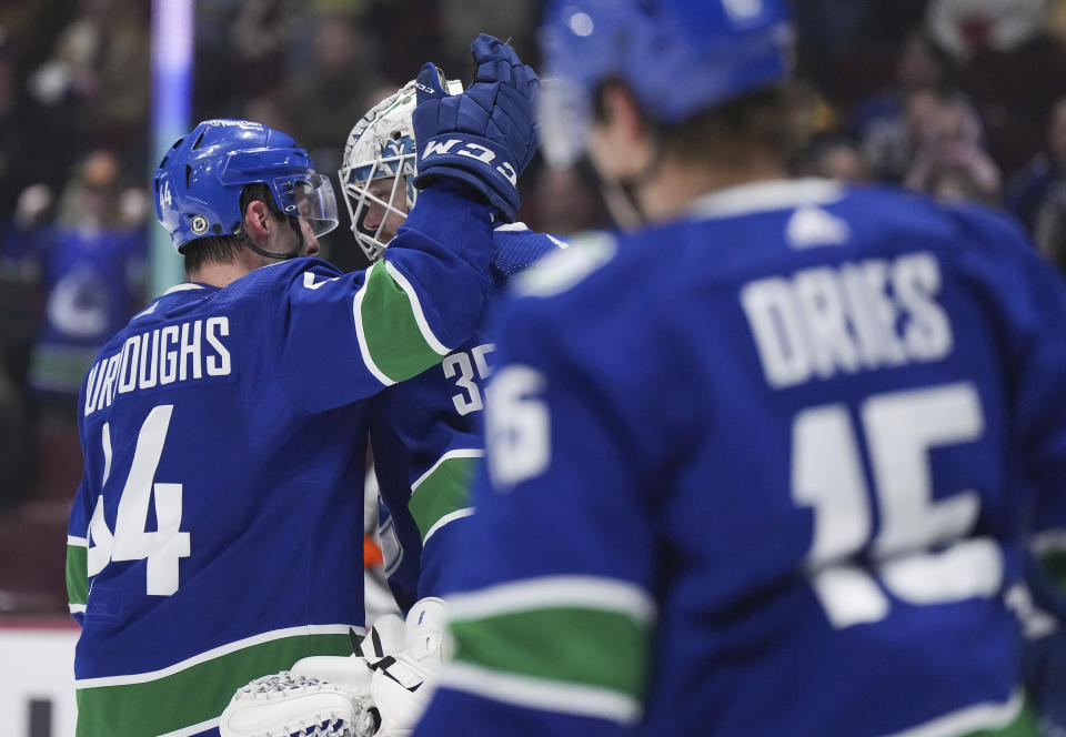 Vancouver Canucks' Kyle Burroughs (44) and goalie Thatcher Demko (35) celebrate after Vancouver defeated the San Jose Sharks in an NHL hockey game in Vancouver, British Columbia, Thursday, March 23, 2023. (Darryl Dyck/The Canadian Press via AP)