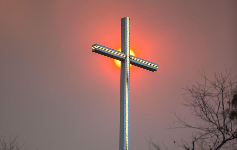 Smoke from a wildfire in California appears behind a church cross. (Photo: Daniel Knighton via Getty Images)