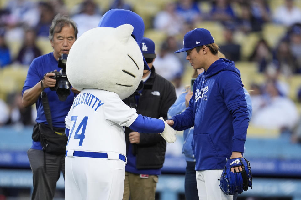 Los Angeles Dodgers pitcher Yoshinobu Yamamoto, right, shakes hands with a Hello Kitty Mascot before the Dodgers' baseball game against the Washington Nationals, Tuesday, April 16, 2024, in Los Angeles. (AP Photo/Marcio Jose Sanchez)