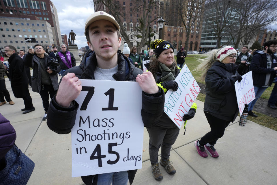 Austin Hunt holds a sign with current and former Michigan State University students during a rally at the capitol in Lansing, Mich., Wednesday, Feb. 15, 2023. Alexandria Verner, Brian Fraser and Arielle Anderson were killed and five other students remain remain in critical condition after a gunman opened fire on the campus of Michigan State University Monday night. (AP Photo/Paul Sancya)