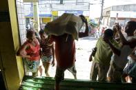 A man carries goods out of a supermarket that was looted during a police strike in Salvador, Bahia state, April 17, 2014. A police strike has unleashed violent crime in Brazil's third-largest city just two months before it is set to welcome hordes of soccer fans for the World Cup, adding to fears about the country's ability to ensure safety during the event. At least 22 people were killed in and around the northeastern city of Salvador after state police went on strike early on Wednesday to demand better pay and other benefits, the Bahia state government said on Thursday, prompting the federal government to dispatch troops to restore order. REUTERS/Valter Pontes (BRAZIL - Tags: CRIME LAW POLITICS CIVIL UNREST SPORT SOCCER WORLD CUP)