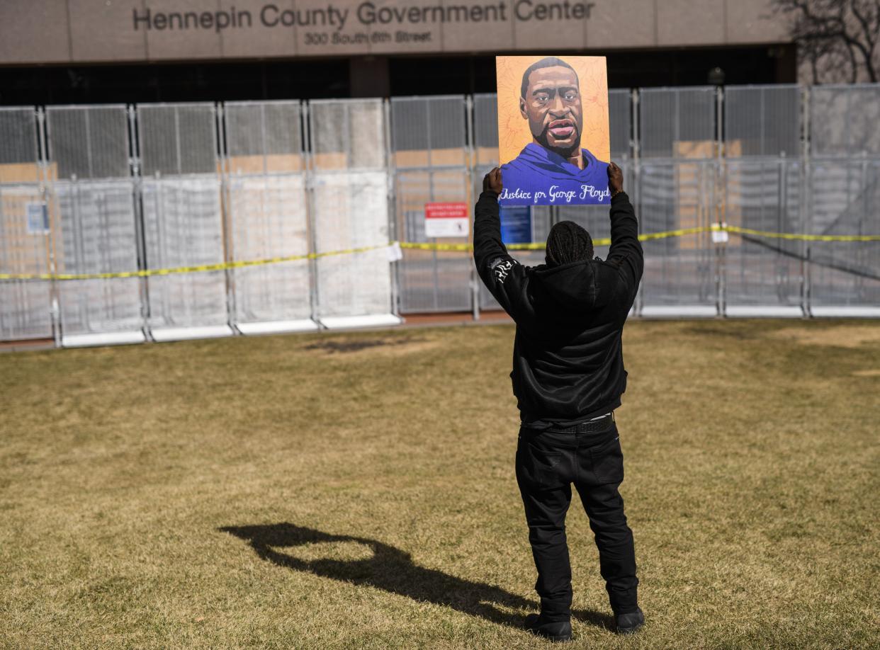 A man holds up a portrait of George Floyd outside the Hennepin County Government Center on March 8, 2021, in Minneapolis, Minnesota.