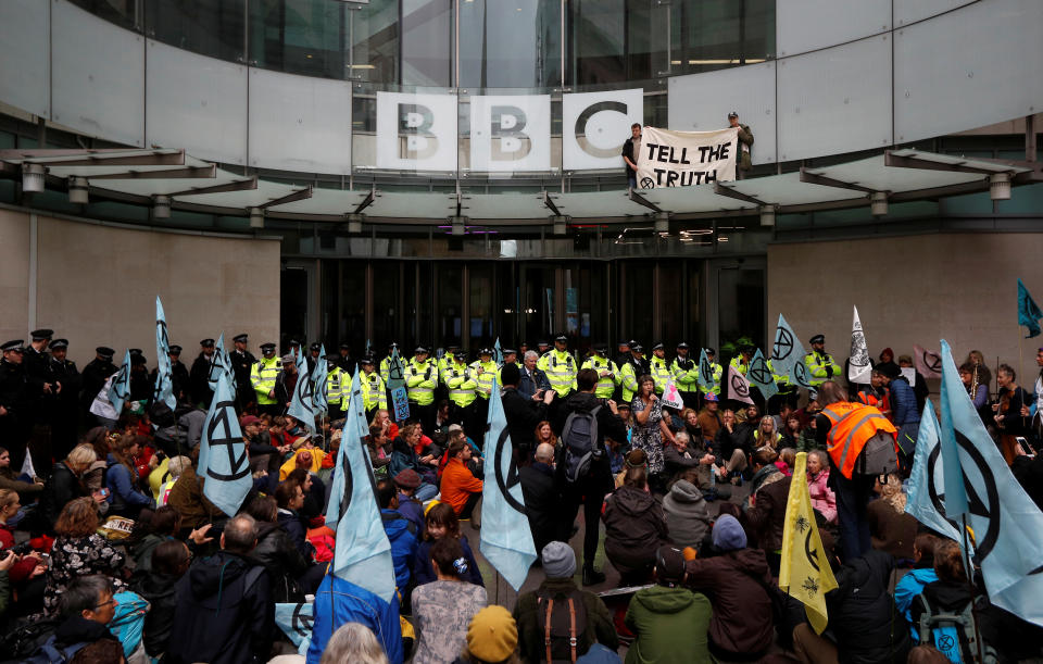 Protesters hold a banner next to the BBC logo at the company's headquarters during an Extinction Rebellion demonstration in London, Britain October 11, 2019. REUTERS/Peter Nicholls