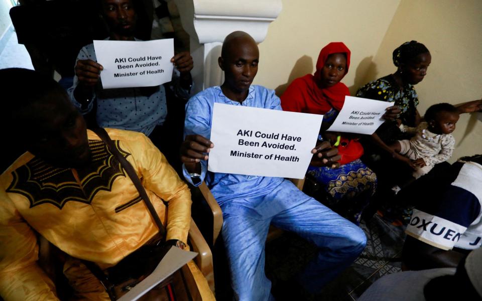 Ebrima Sagnia holds up a sign during a news conference, calling for justice for the deaths of children linked to contaminated cough syrups, in Serekunda, Gambia