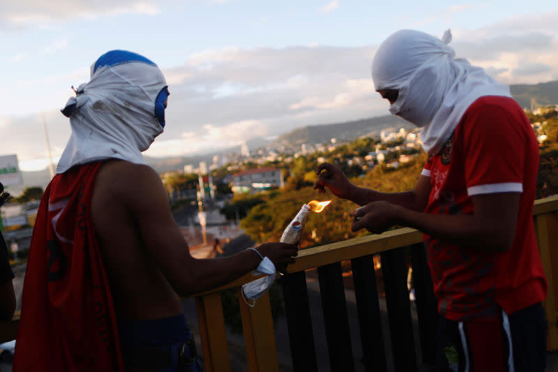 Des manifestants allument un cocktail Molotov, à Tegucigalpa au Honduras. Le gouvernement du Honduras a suspendu les droits constitutionnels afin de donner à la police et à l'armée des pouvoirs élargis pour contenir les violences, qui ont déjà fait un mort, engendrées par la contestation du déroulement du processus électoral, a dit vendredi un responsable gouvernemental. /Photo prise le 1er décembre 2017/REUTERS/Edgard Garrido