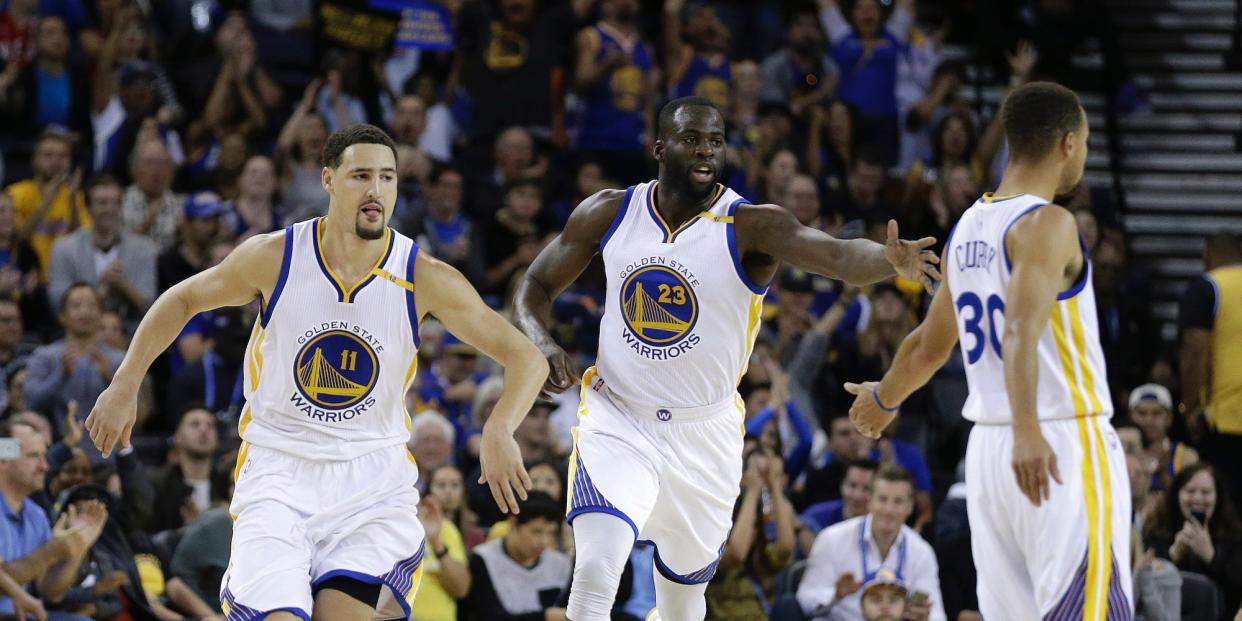 Klay Thompson, Draymond Green, and Stephen Curry run down the floor high-fiving during a game in 2016.