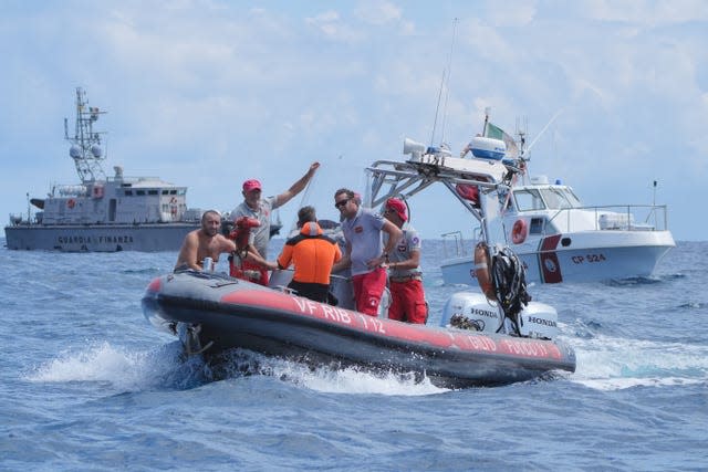 Several men in a small boat with two boats behind