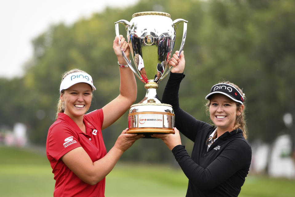 Canada's Brooke Henderson holds the trophy with her sister and caddie Brittany as she celebrates her win at the Women's Canadian Open golf tournament in Regina, Saskatchewan, Sunday Aug. 26, 2018. (Jonathan Hayward/The Canadian Press via AP)