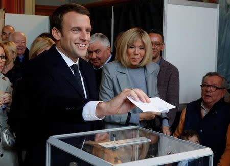 Emmanuel Macron (L), head of the political movement En Marche !, or Onwards !, and candidate for the 2017 French presidential election, casts his ballot in the first round of 2017 French presidential election at a polling station in Le Touquet, northern France, April 23, 2017. At C, his wife Brigitte Trogneux. REUTERS/Philippe Wojazer