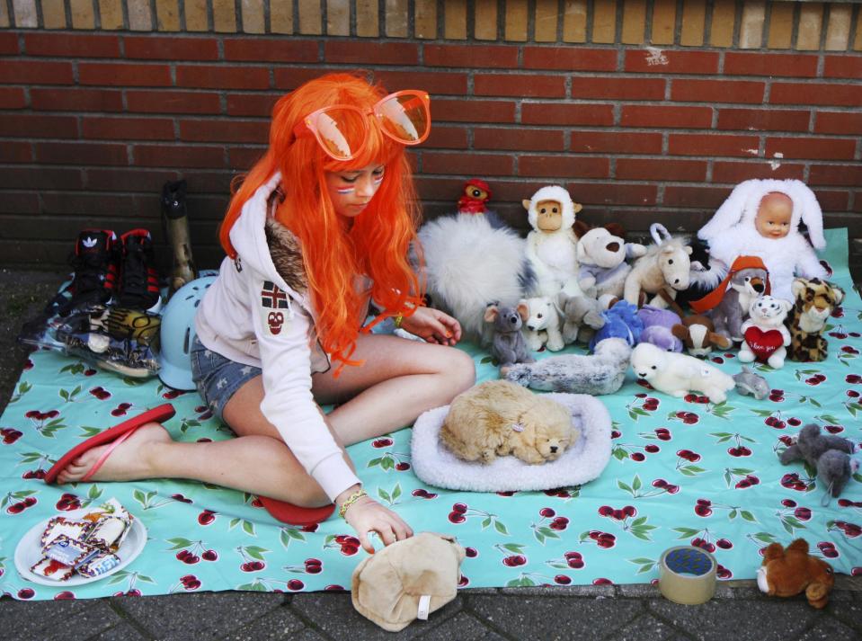 A girl prepares to sell her goods at the annual free market during festivities marking King's Day in Amsterdam, Netherlands, Saturday, April 26, 2014. The Dutch celebrate the first ever King's Day, a national holiday held in honor of the newly installed monarch, King Willem Alexander. King's Day replaces the traditional Queen's Day. (AP Photo/Margriet Faber)