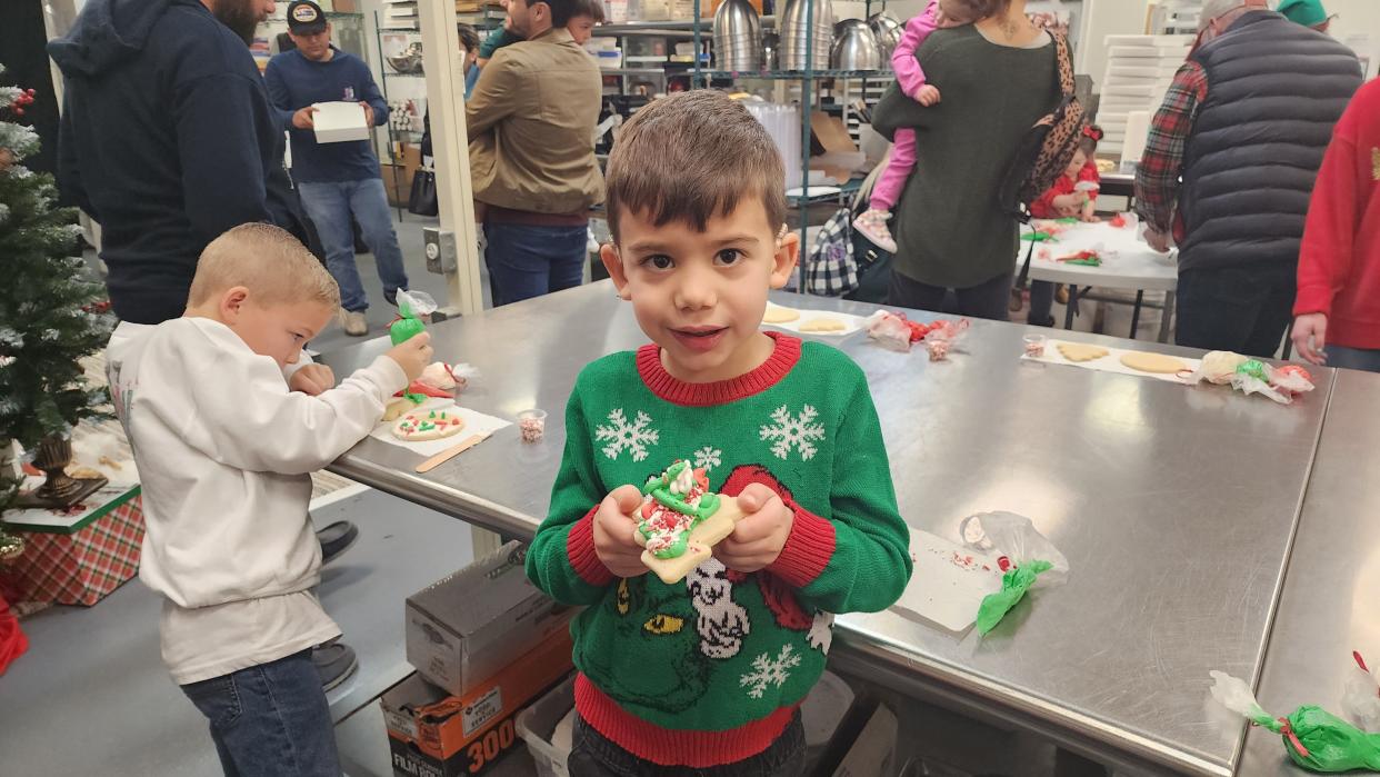 A young boy shows off his heavily decorated cookie for Santa Saturday at the Cake Company of Canyon.