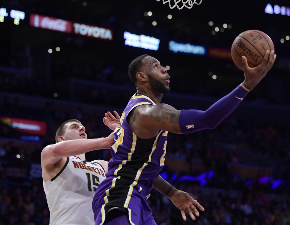 LeBron James, derecha, de los Lakers de Los Ángeles, lanza el balón ante la marca de Nikola Jokic, de los Nuggets de Denver, durante un partido de la NBA el miércoles 6 de marzo del 2019, en Los Ángeles. (AP Foto/Mark J. Terrill)