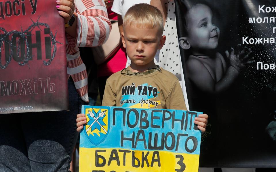 Un niño ucraniano sostiene un cartel que dice 
