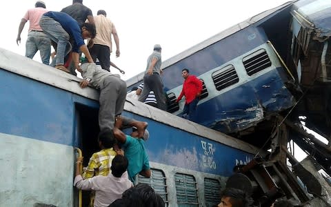 Local residents look for survivors on the wreckage of train carriages after the derailment - Credit: AFP