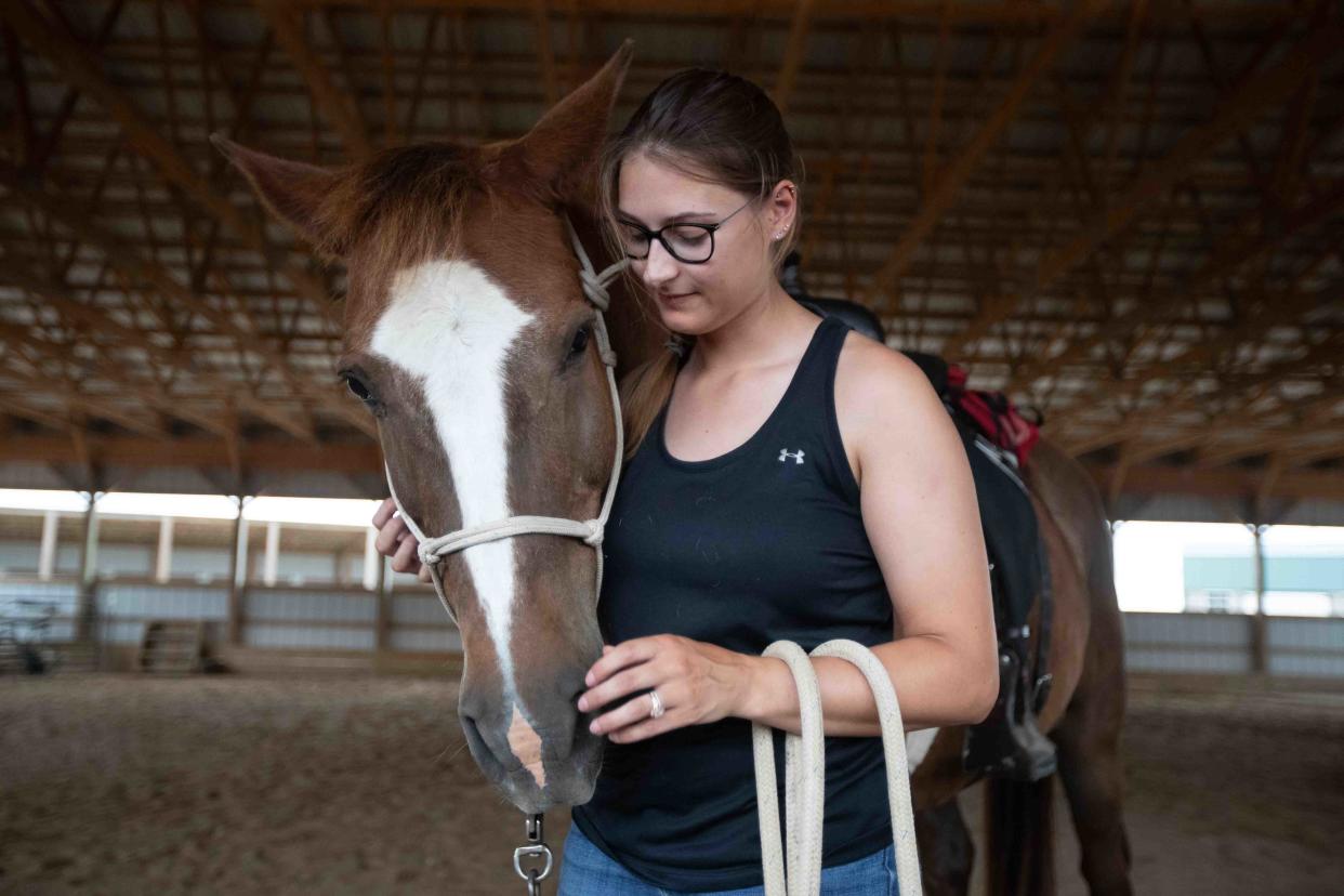 Titus, a 23-year-old appendix thoroughbred Gelding horse, is caressed by Samantha Schneider after going through a few training routines at Rainbow Meadows on June 18. Schneider is adopting Titus.