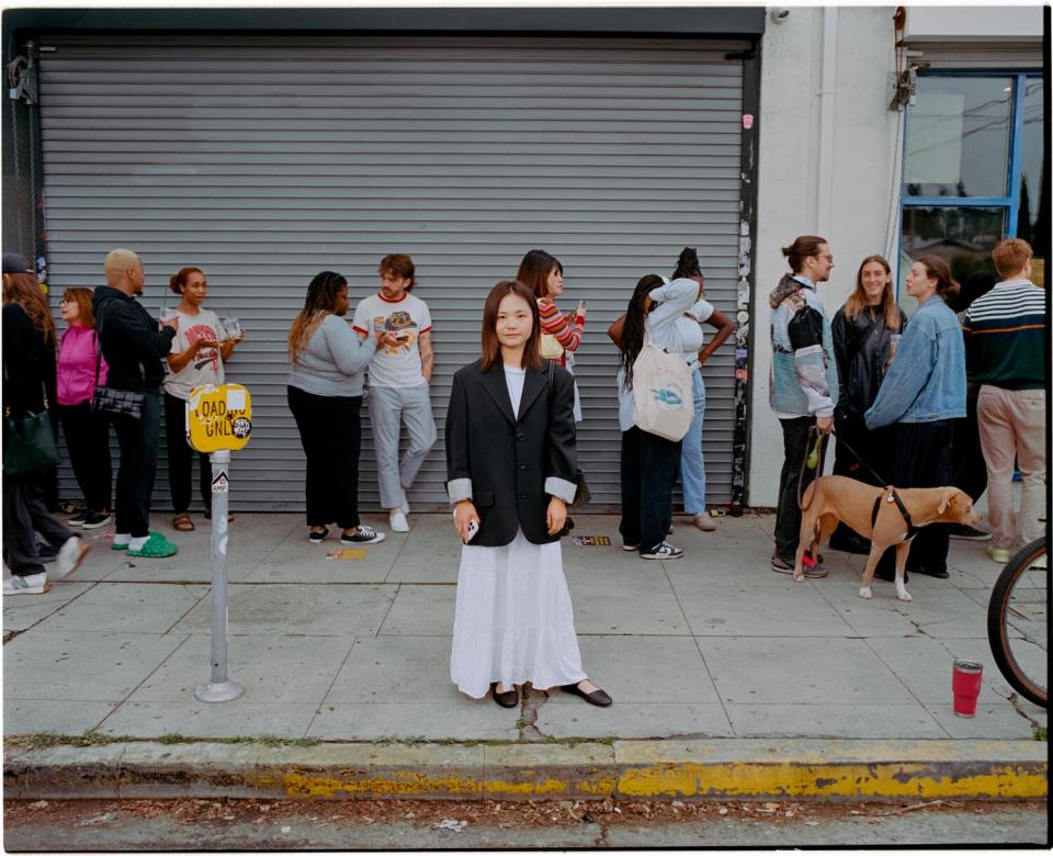 Woman in a white skirt stands outside a line.