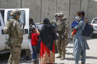 In this image provided by the U.S. Marines, soldiers assigned to 3rd Brigade, 10th Mountain Division escort evacuees to the terminal for check-in during an evacuation at Hamid Karzai International Airport in Kabul, Afghanistan, Friday, Aug. 20, 2021. (Lance Cpl. Nicholas Guevara/U.S. Marine Corps via AP)