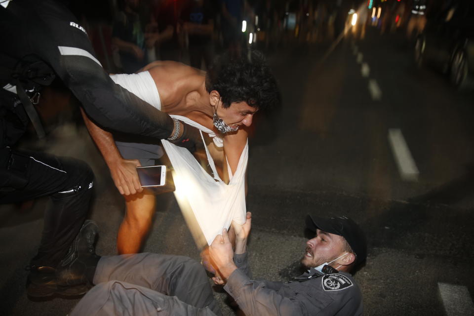 Israeli police officers arrest an Israeli protester during a demonstration against lockdown measures that they believe are aimed at curbing protests against prime minister Benjamin Netanyahu Tel Aviv, Israel, Saturday, Oct. 3, 2020. (AP Photo/Ariel Schalit)